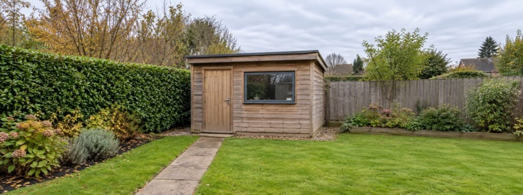 Small stand-alone timber garden building in a UK garden, the kind of small detached building that can be exempt from an EPC